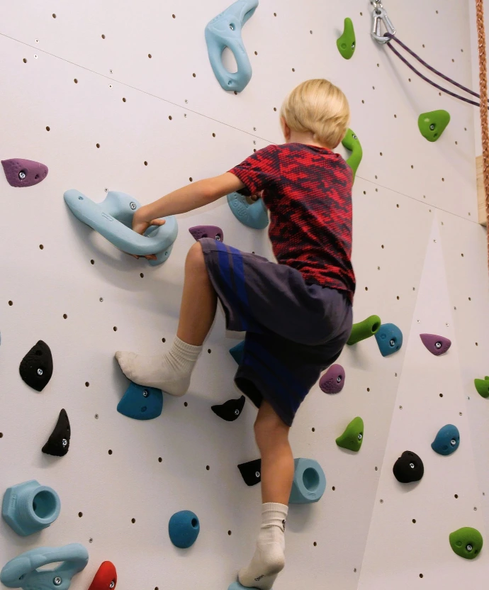 Kind klettert an der Boulderwand im ANKERZEIT-Freiraum