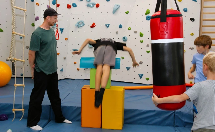 Kinder spielen am Boxsack, ein Erwachsener schaut zu im ANKERZEIT-Freiraum