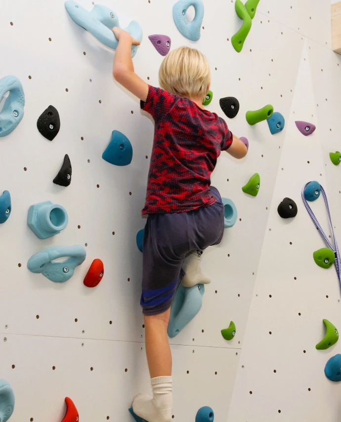 Kind klettert an der Boulderwand im ANKERZEIT-Freiraum