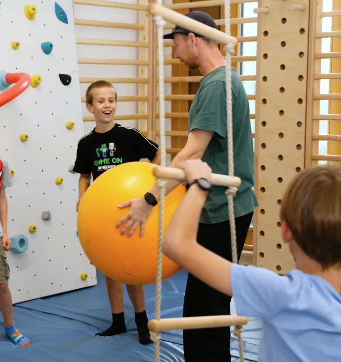 Kinder spielen mit einem orangen Gymnastikball im ANKERZEIT-Freiraum
