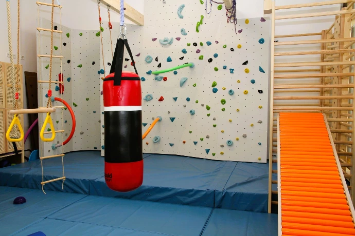 Boxsack und orange Rollenrutsche vor der Boulderwand im ANKERZEIT-Freiraum