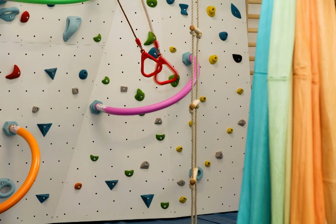 Boulderwand mit bunten Griffen und Ringen im ANKERZEIT-Freiraum
