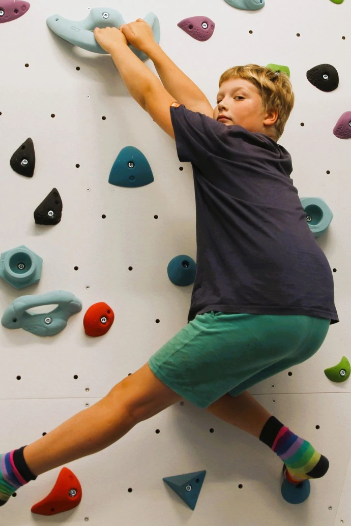 Kind klettert an der Boulderwand im ANKERZEIT-Freiraum