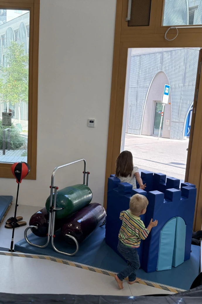 Kinder spielen auf blauen Matten am Fenster im ANKERZEIT-Freiraum
