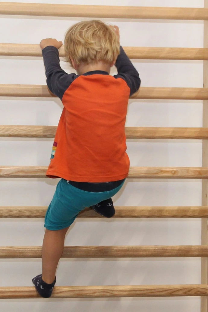 Kind klettert an der Sprossenwand im ANKERZEIT-Freiraum