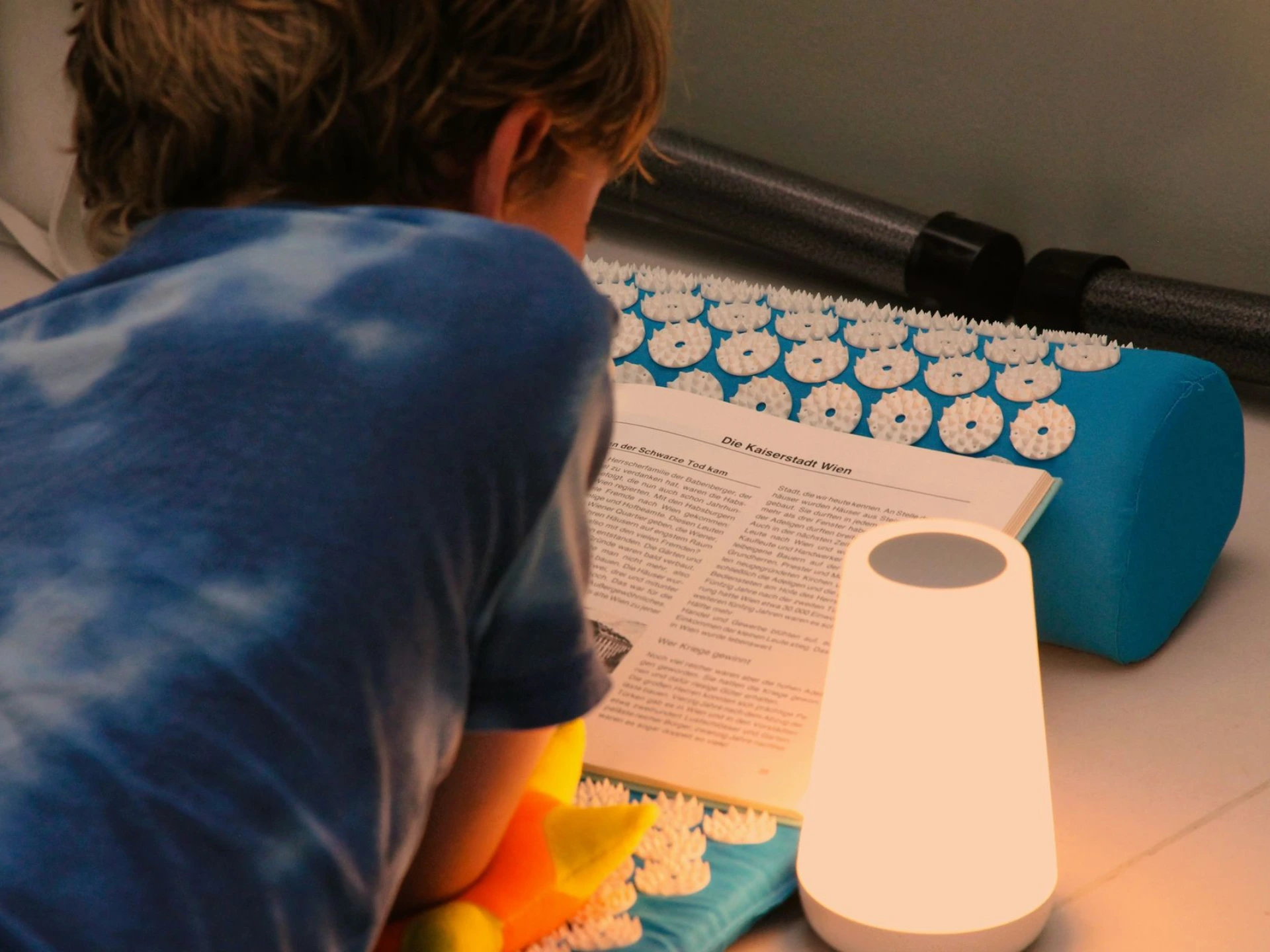 Kind liegt auf einer Akupressurmatte neben einer Lampe in der ANKERZEIT-Ruheinsel