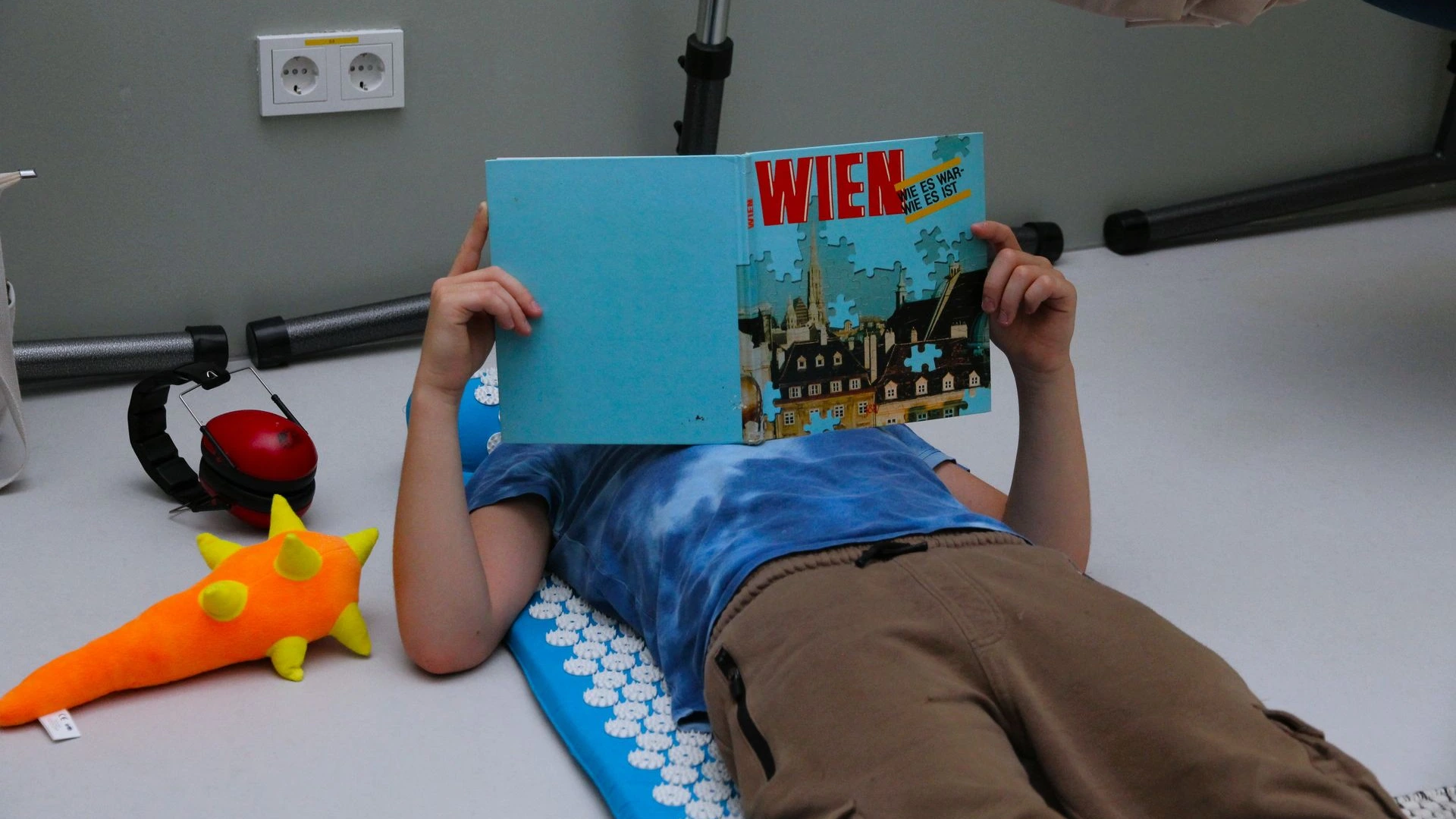 Kind liegt am Boden und liest ein Buch in der ANKERZEIT-Ruheinsel