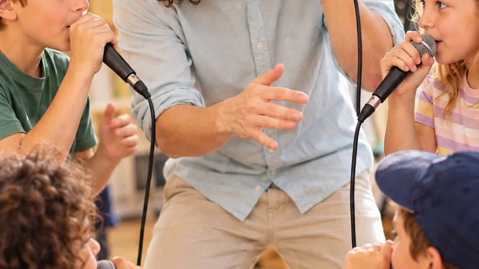 Beatbox-Workshop: Person hält ein Mikrofon, Kinder sind dabei