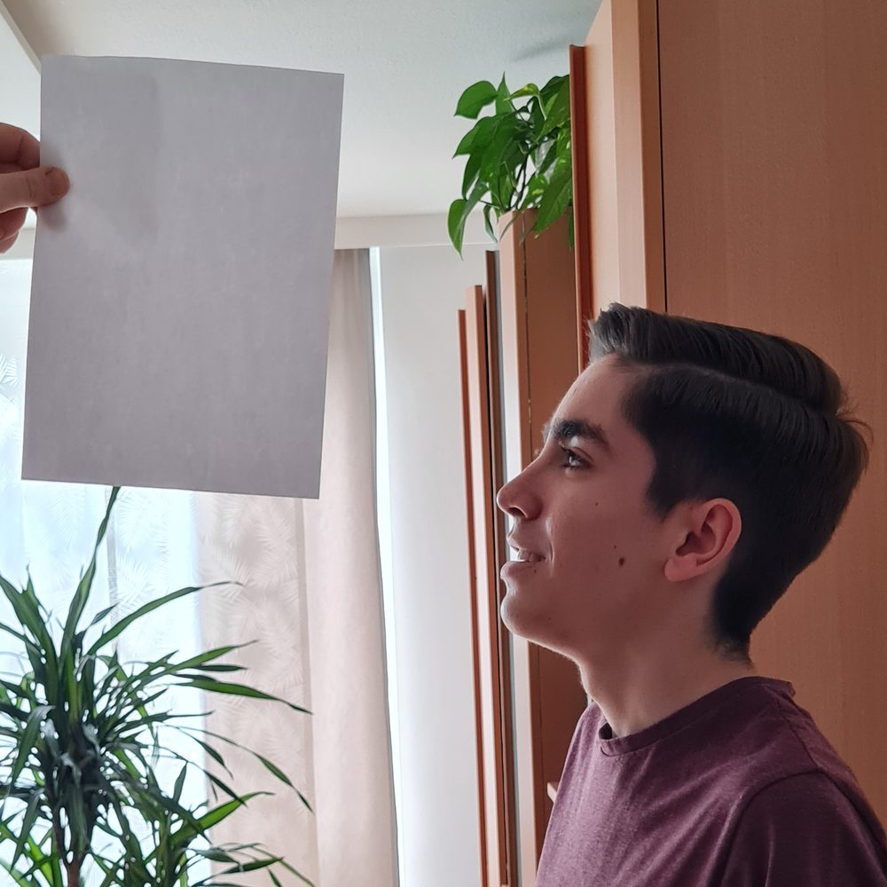 Jugendlicher bei einer Augenübung mit Papier, Evolutionspädagogik Einzelsetting