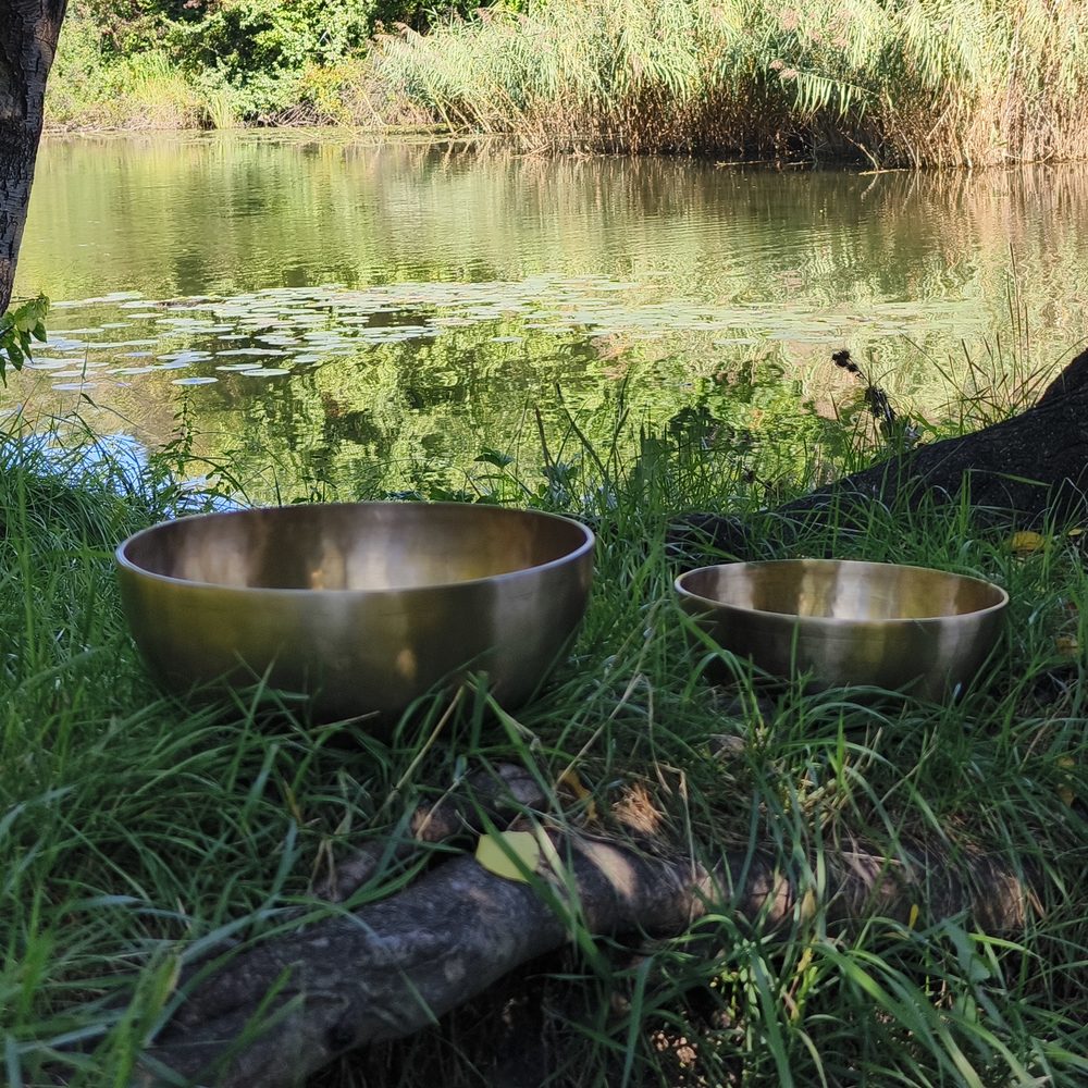 Zwei Klangschalen im Gras am Wasser