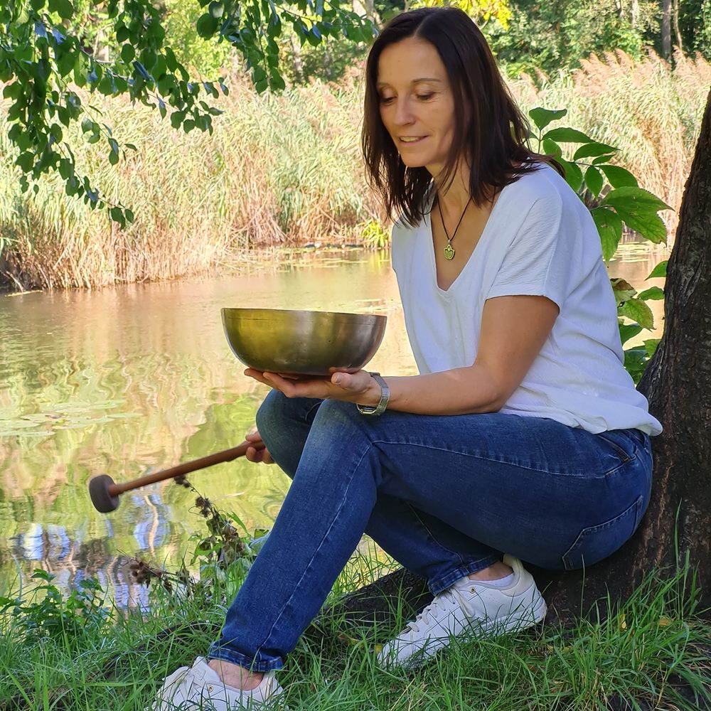 Petra Göls hält eine Klangschale im Grünen